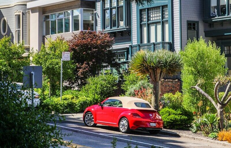 red coupe parking near house during daytime